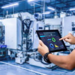Hands holding tablet on blurred automation machine as background